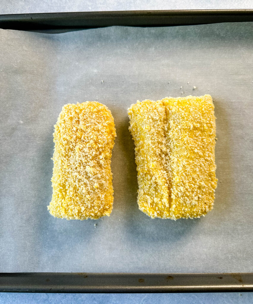 breaded fish fillets on parchment paper and a sheet pan