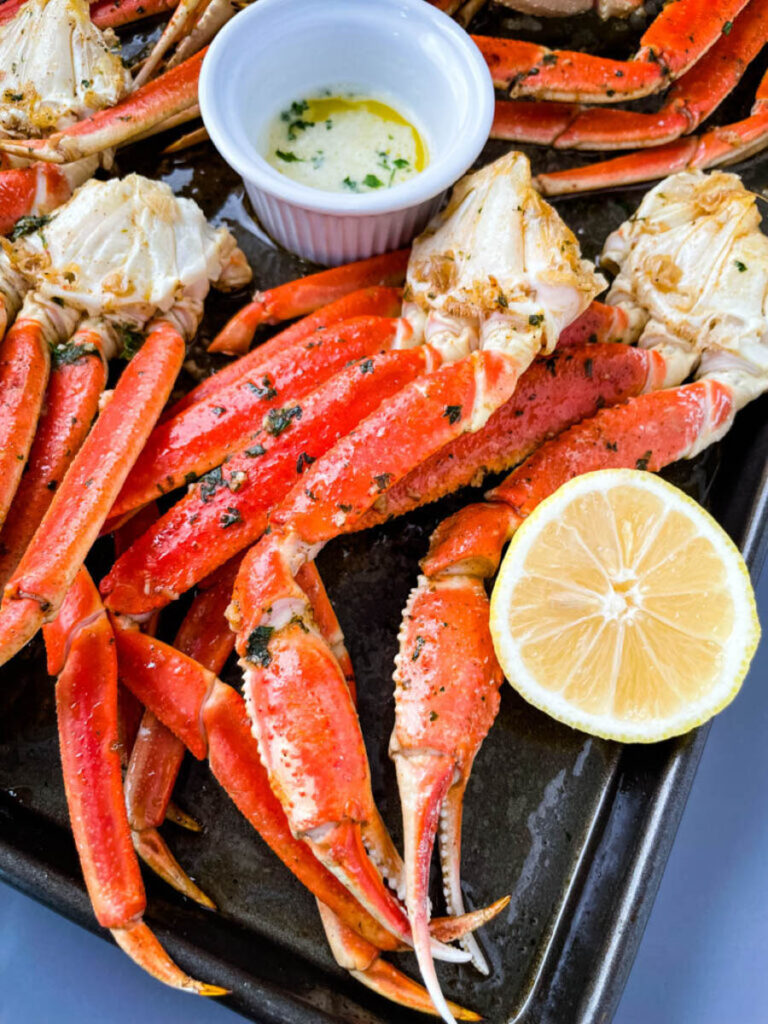 cooked crab legs on a plate with fresh lemon and butter