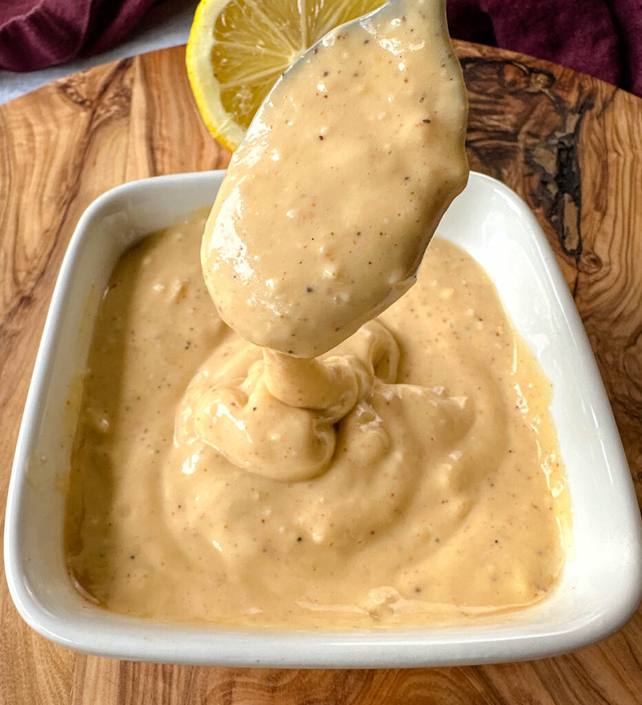 a spoon filled with remoulade sauce in a white bowl