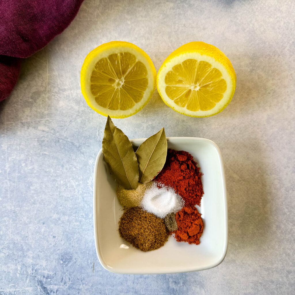 Cajun spices, bay leaves, and fresh lemon on a flat surface