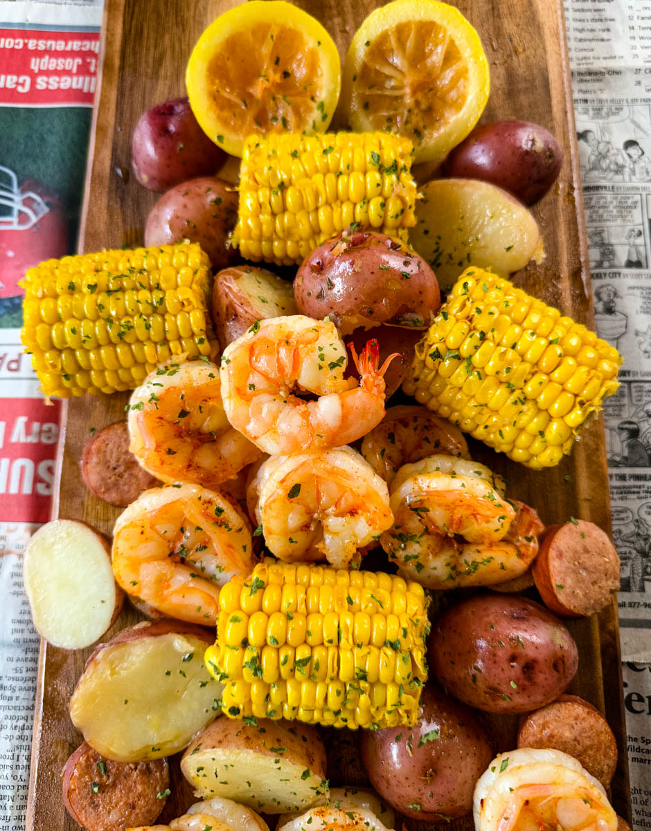Shrimp boil with andouille sausage, red potatoes, and corn on the cob on a flat surface with newspaper
