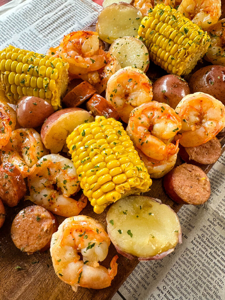 shrimp boil with andouille sausage, red potatoes, and corn on the cob on a flat surface with newspaper