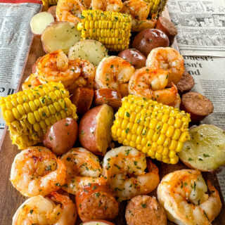 shrimp boil with andouille sausage, red potatoes, and corn on the cob on a flat surface with newspaper