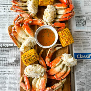Dungeness crab legs on a platter with corn on the cob and lemon garlic butter sauce