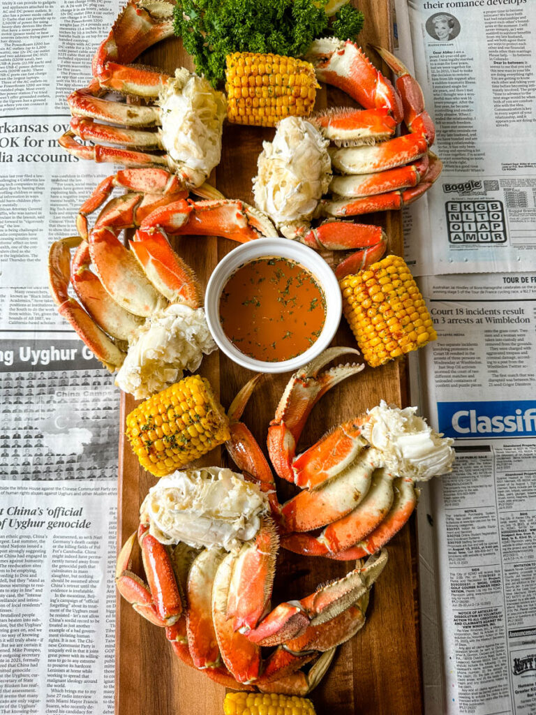 Dungeness crab legs on a platter with corn on the cob and lemon garlic butter sauce