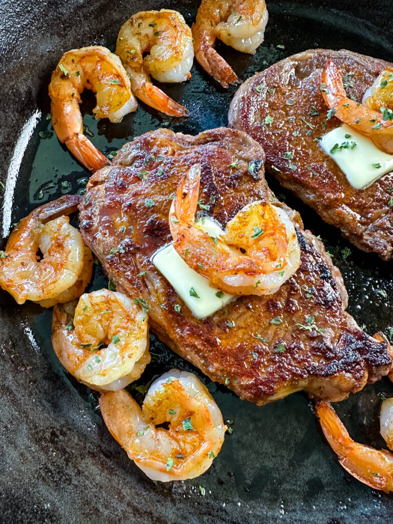 steak and shrimp with butter in a cast iron skillet