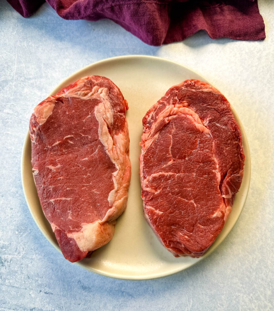 raw ribeye steaks on a plate