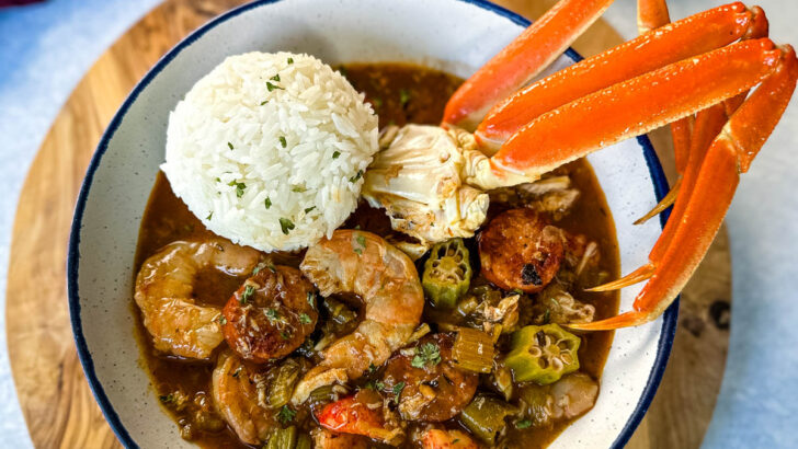Cajun seafood gumbo with shrimp and crab meat and crab legs with rice in a white bowl