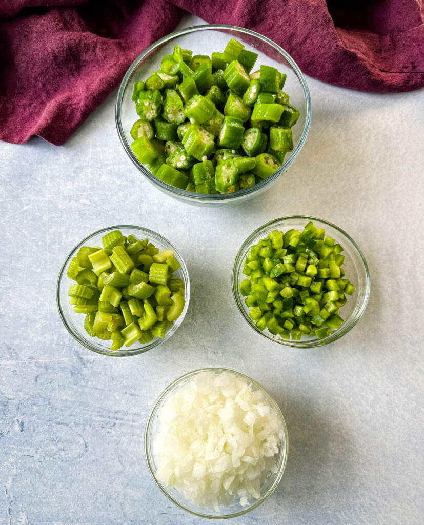 cut okra, diced green bell peppers, diced white onions, and diced celery in separate glass bowls