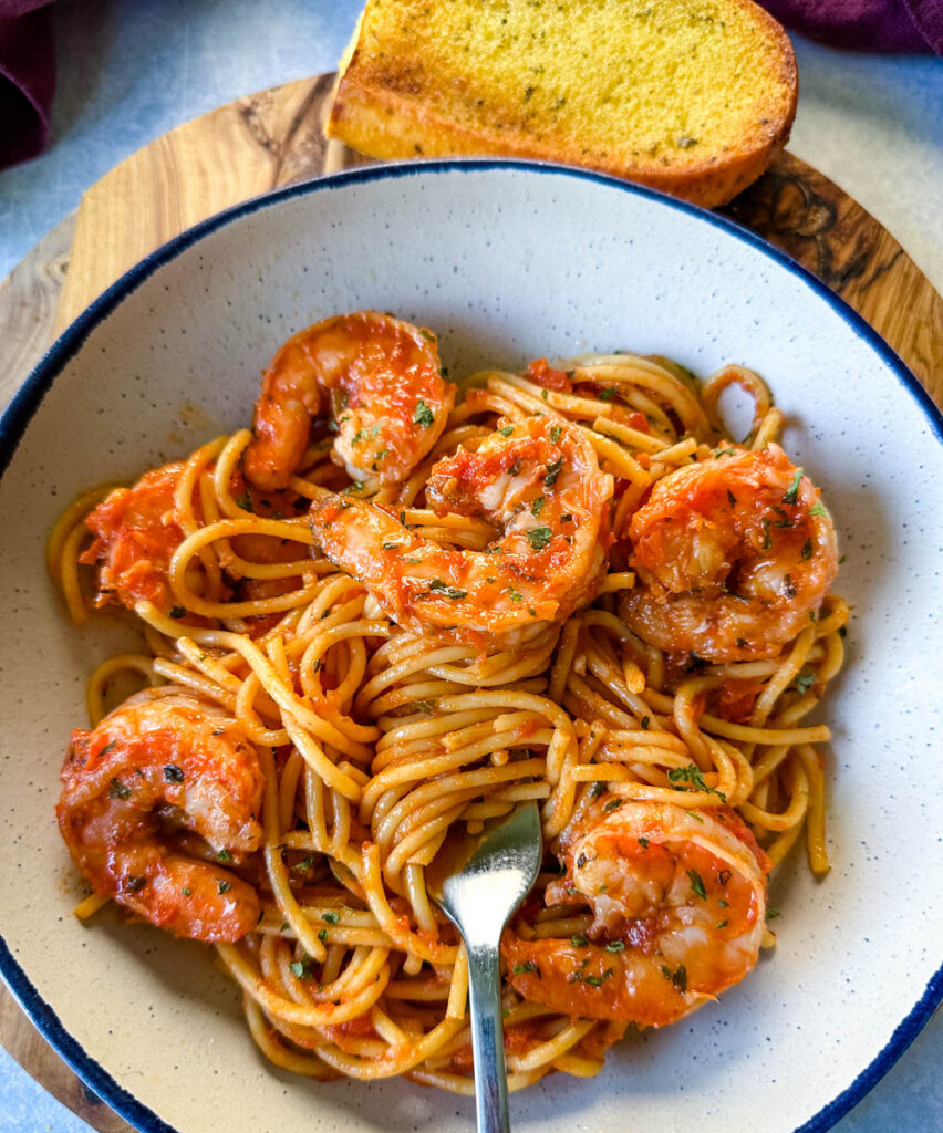 shrimp spaghetti with garlic in a white bowl with a fork