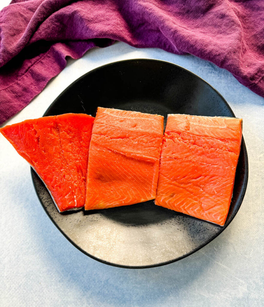 raw salmon fillets on a black plate