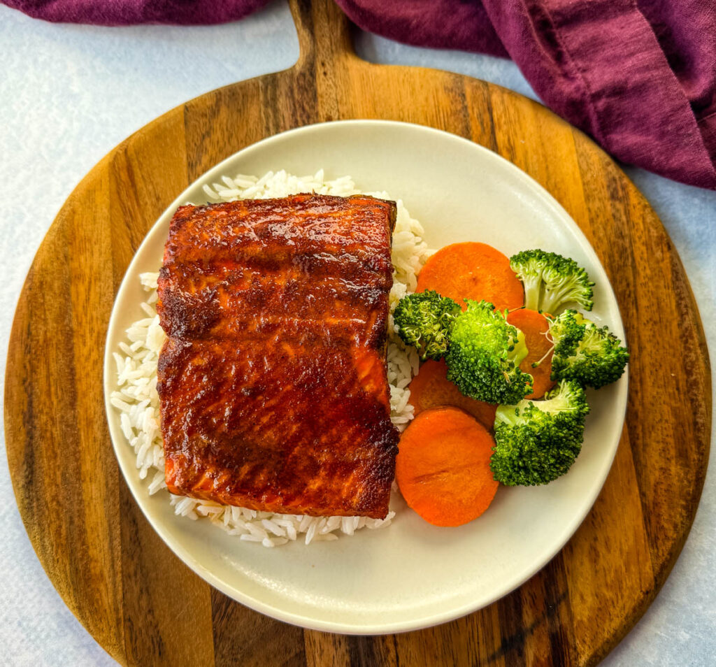 salmon glazed with brown sugar, butter, soy sauce with vegetables on a white plate