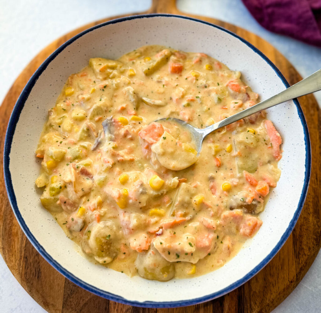 creamy salmon chowder with corn and potatoes in a white bowl with a spoon