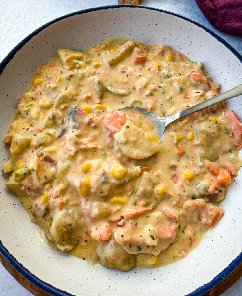 creamy salmon chowder with corn and potatoes in a white bowl with a spoon