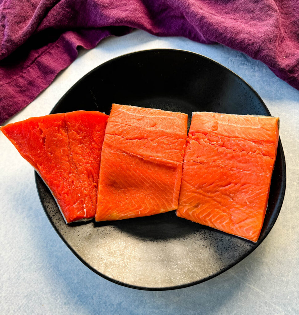 raw salmon fillets on a black plate
