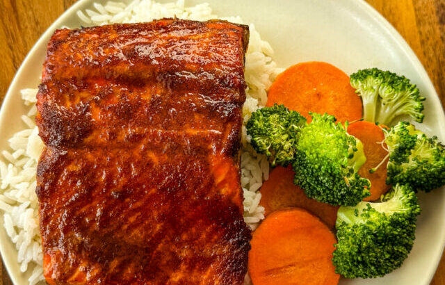 salmon glazed with brown sugar, butter, soy sauce with vegetables on a white plate