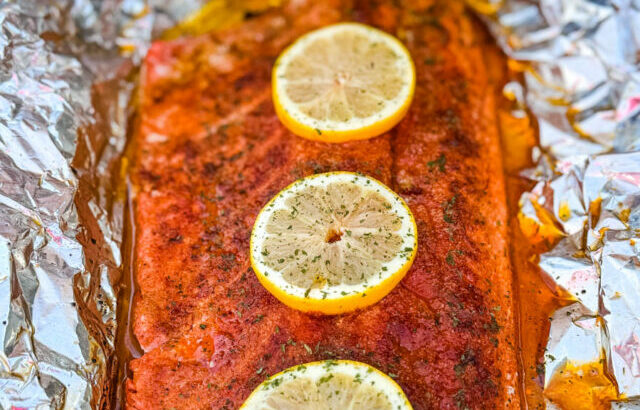 salmon in foil on a grill with fresh lemons