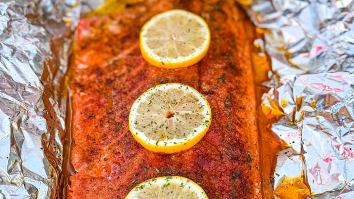 salmon in foil on a grill with fresh lemons
