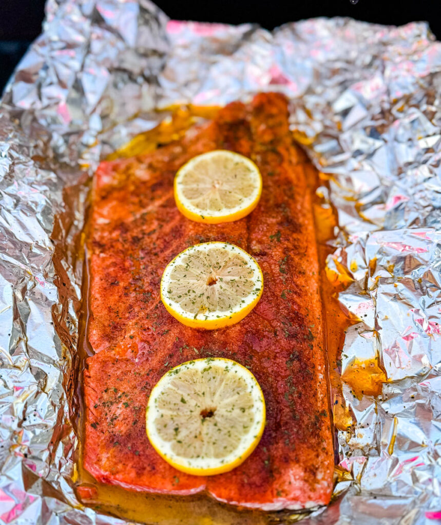 salmon in foil on a grill with fresh lemons