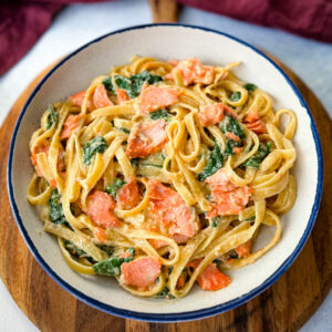 salmon Fettuccine Alfredo with spinach in a white bowl