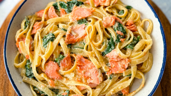 salmon Fettuccine Alfredo with spinach in a white bowl