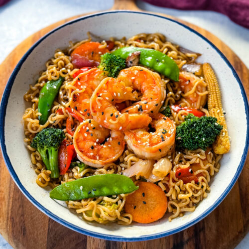 shrimp stir fry with noodles, vegetables, and a homemade sauce in a white bowl