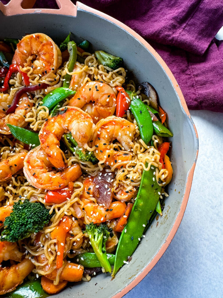 shrimp stir fry with noodles, vegetables, and a homemade sauce in a skillet