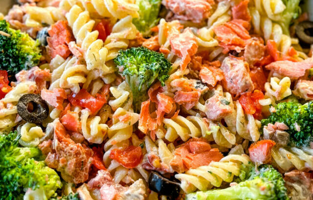 salmon pasta salad with broccoli and tomatoes in a white bowl