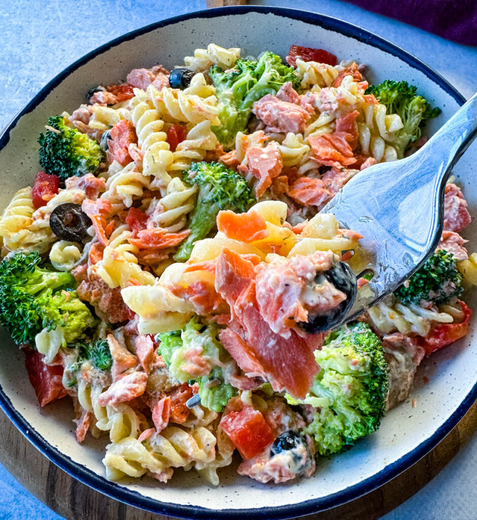 forkful of salmon pasta salad with broccoli and tomatoes