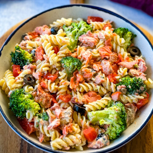 salmon pasta salad with broccoli and tomatoes in a white bowl