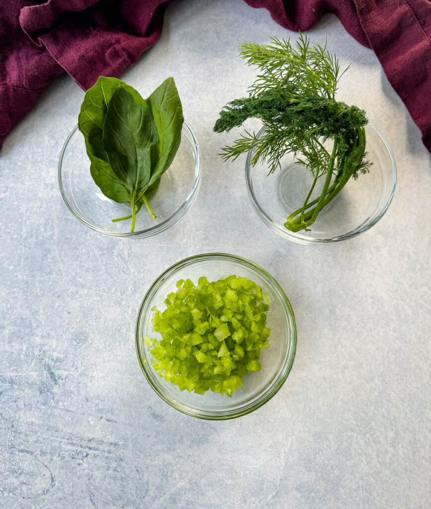 diced celery, fresh basil, and fresh dill in separate glass bowls
