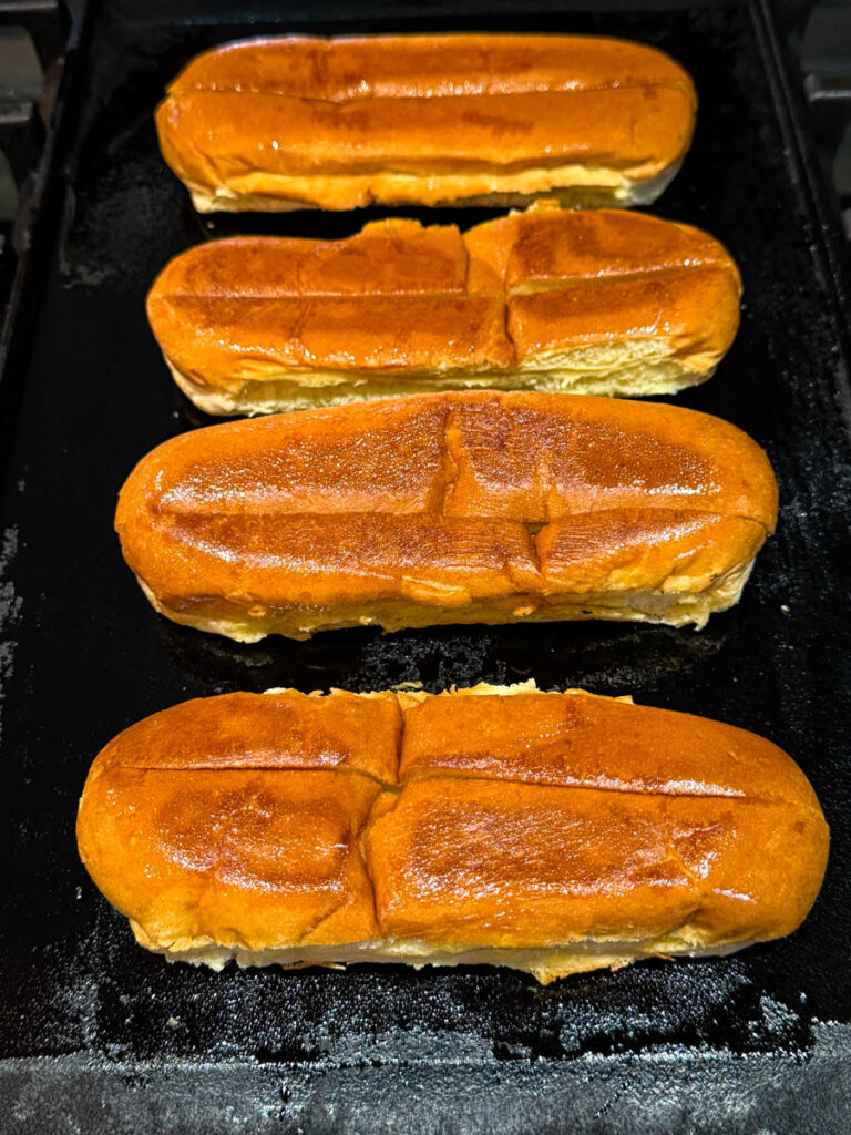 toasted top sliced hot dog buns in a cast iron skillet